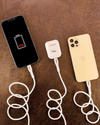 Lightning USB-C Corded threaded charging cables plugged into apple iphone 13 13 pro iphone 12 12 pro and airbuds airpod kickpower xbuds on rustic leather background in looped design bright white